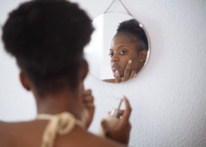 focused-woman-applying-cream-on-face-in-bathroom-4177827